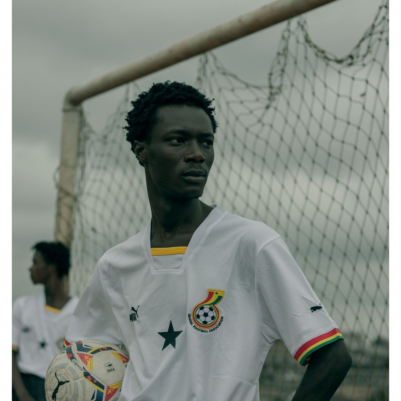 Un jeune footballeur en maillot blanc du Ghana devant un but