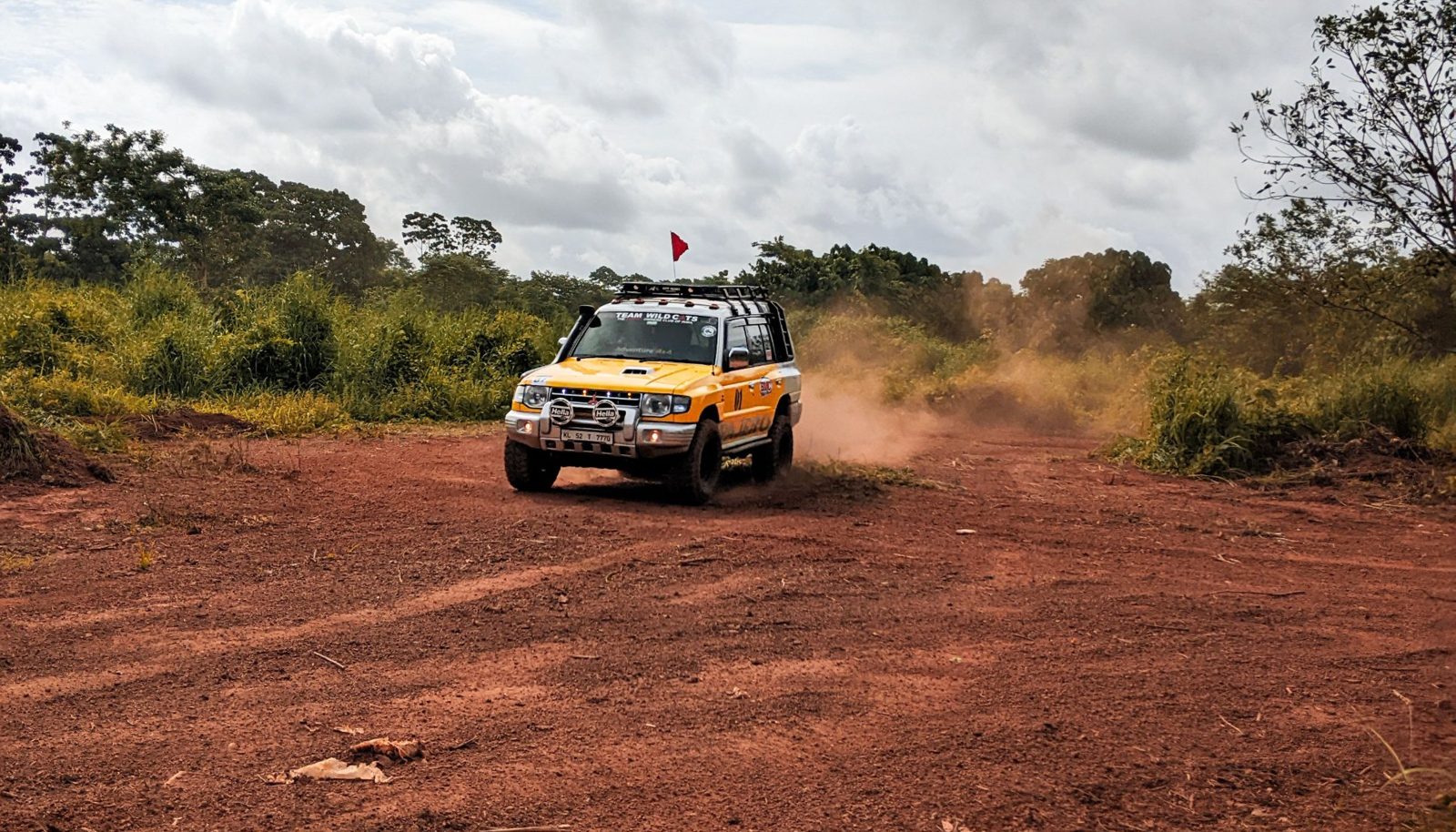 Une voiture de rallye soulevant de la poussière sur une piste de terre rouge